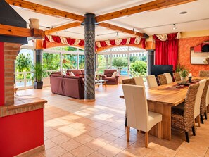 A spacious outdoor dining area with a wooden table and wicker chairs, surrounded by a covered patio with red curtains and a large pillar. - Villa Vedorna, pool, whrilpool, sauna, t. tennis, poker tables, playground,.. (Pomer)