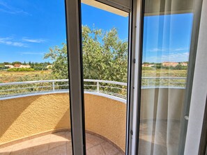 A balcony with a view of a landscaped area and distant buildings.