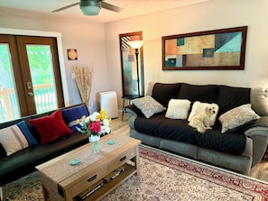 A living room with a sofa, a coffee table, a rug, and a painting on the wall.