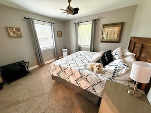 A bedroom with a bed, a ceiling fan, a standing lamp, and a dog.