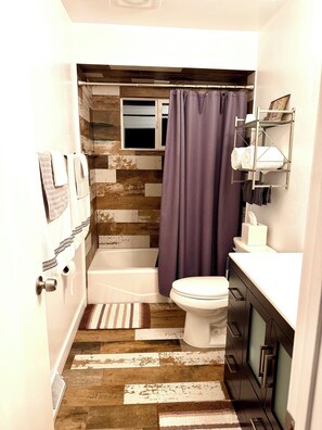 A bathroom with a bathtub, toilet, and shower curtain. - Beautiful 2 Bedroom Duplex (Fond du Lac)
