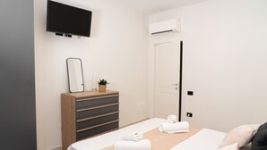 Ett hotellrum med en säng, en byrå, en tv och en luftkonditioneringsanläggning.