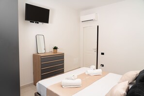 A hotel room with a bed, a dresser, a television, and an air conditioning unit. - Via Niccolò Tommaseo 4 - appartamento 1 (Napoli)