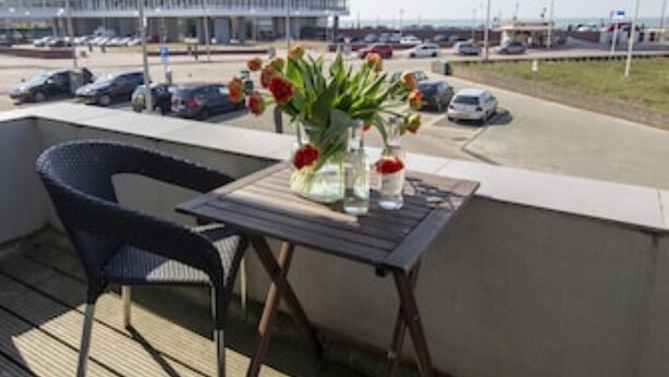 A balcony with a table, chairs, and a vase of flowers. - Seapoint, apartment with balcony and sea view (Zandvoort)