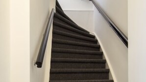 A carpeted staircase with a handrail and a wooden floor. - Seapoint, apartment with balcony and sea view (Zandvoort)