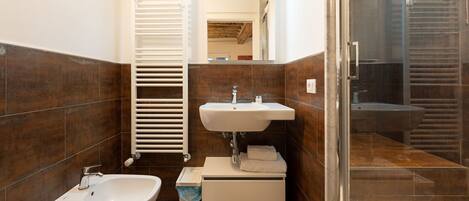 A modern bathroom with a bidet, sink, and towel rack.