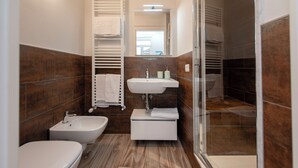Une petite salle de bain équipée d’un bidet, d’un lavabo et d’un miroir.
