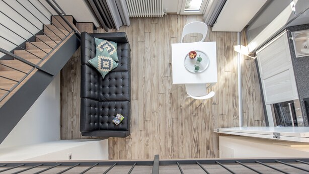 A modern loft-style living space with a black leather sofa, a white coffee table, and a staircase. - Zannetti 401 Top floor (Firenze)