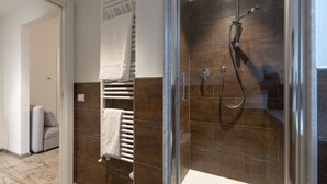 A modern bathroom with a glass shower enclosure, a built-in towel rack, and a visible toilet.