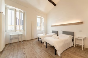 A bedroom with two beds, a desk, and a window with a view of buildings. - Zannetti 301 Compact (Firenze)