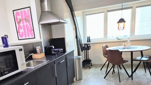 Una cucina moderna con mobili scuri, un forno a microonde, un piano cottura e un'area pranzo con tavolo e sedie.