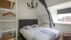 Una camera da letto con un letto, una lampada a sospensione, una finestra vista e un armadio con scaffali e un appendiabiti.