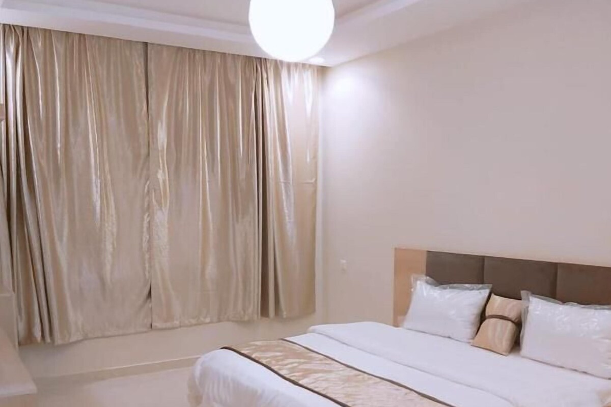 Ein geräumiges Schlafzimmer mit einem großen Bett, einem Kopfteil und einer Deckenleuchte.
