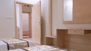 Ein Hotelzimmer mit zwei Betten, einem kleinen Tisch und einem Spiegel an der Wand.