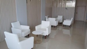Eine moderne Hotelhalle mit weißen Ledersofas, einem runden Couchtisch und einem dekorativen Metallkorb.