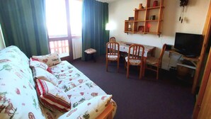 Un dormitorio con cama, escritorio y televisión.