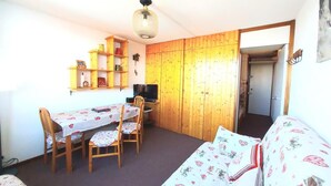 Habitación compacta con mesa, sillas, cama, televisor y paneles de madera.
