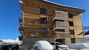 Un edificio de madera de varios pisos con balcones, con la leyenda "TAIGA", en un entorno nevado.