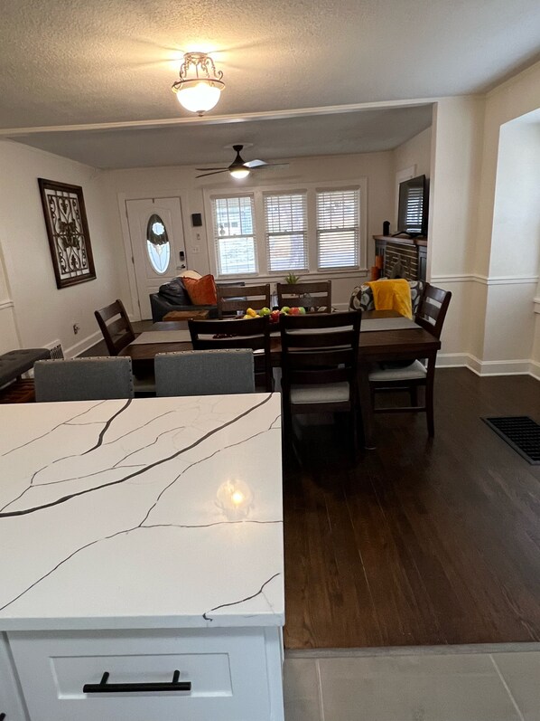 A dining area with a marble table, dark wooden chairs, and a ceiling fan.