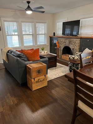 A living room with a fireplace, a sofa, a coffee table, and wooden crates labeled 'George Buckler Genuine Tennessee Whiskey'.