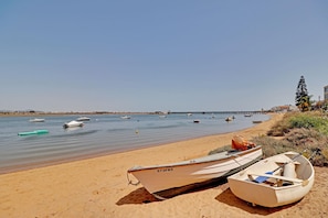 A sandy beach with several boats, including a rowboat and a small motorboat, docked near the shore.