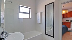 Un bagno con vasca, doccia, lavandino e finestra.
