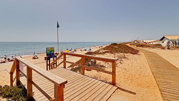 Una passerella di legno che conduce a una spiaggia sabbiosa con vista sull'oceano.
