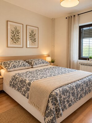 A bedroom with a bed, bedside tables, a window with curtains, and wall-mounted artwork.
