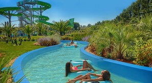 A water park with a long, winding water slide surrounded by lush greenery.