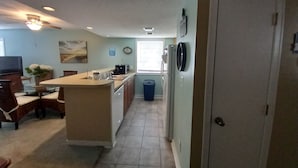 Una cocina compacta con una isla central, un área de comedor con sillas, un refrigerador y un bote de basura.
