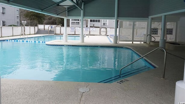 Una piscina interior con techo cubierto, bordes transparentes y un puesto de socorrista.