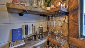 Eine Barbereich mit Regalen, die Gläser, ein Cocktailbuch und Bartools beherbergen.