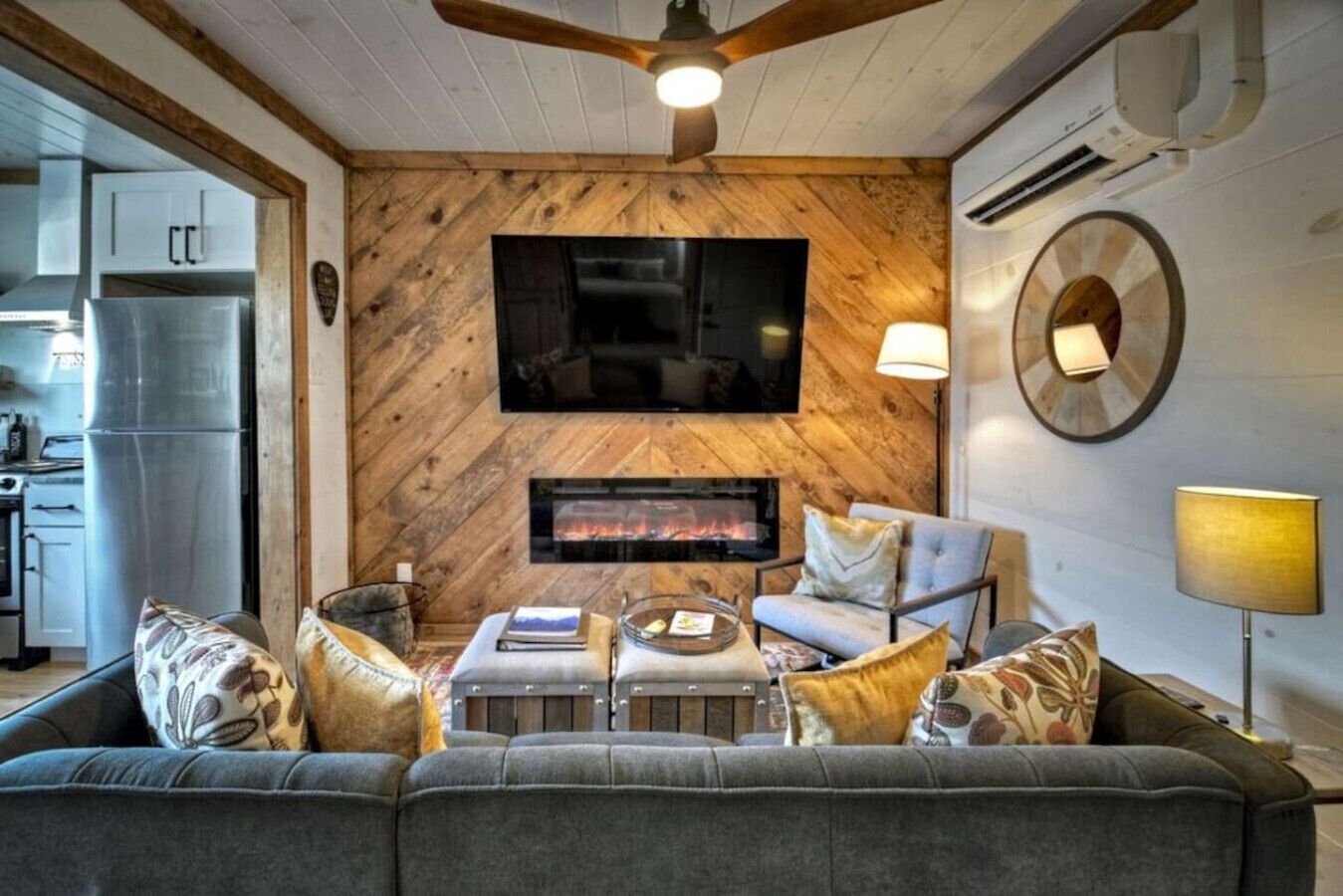 A cozy living room with a fireplace, a sofa, and a television mounted on a wooden wall.