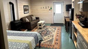 A compact room with a sofa, a small table, a rug, a kitchenette, and a door. - Quick walk to trails, Close to shops, restaurants (Sedona)
