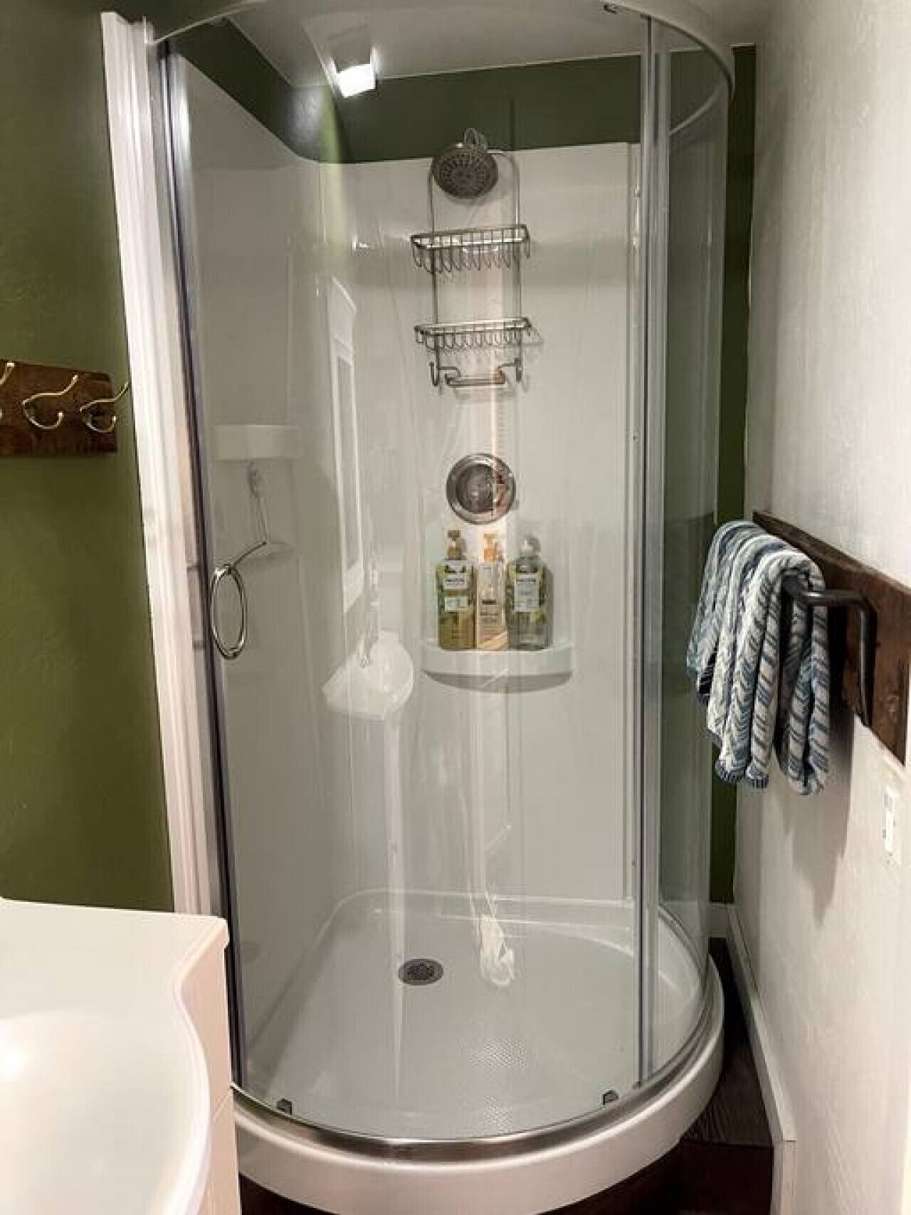 Ducha con mampara de vidrio y estante integrado para artículos de aseo.