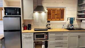 A modern kitchen with a built-in microwave, coffee maker, and toaster. There is a window with wooden shutters and a sink with a faucet. - Quick walk to trails, Close to shops, restaurants (Sedona)