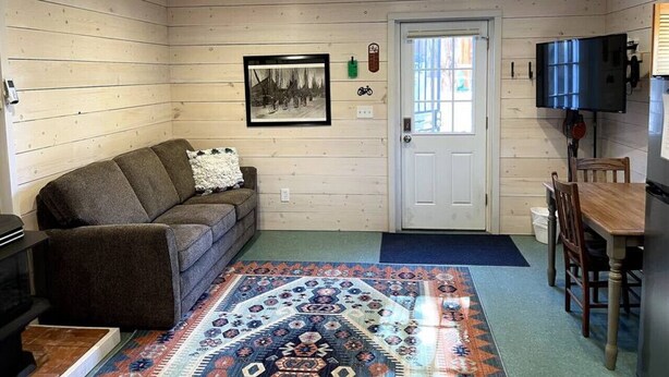 A cozy cabin interior with a sofa, a dining table, and a patterned rug. - Quick walk to trails, Close to shops, restaurants (Sedona)