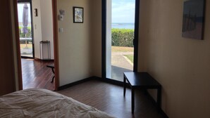 A bedroom with a bed, a small table, and a view of the outdoors through a sliding door.