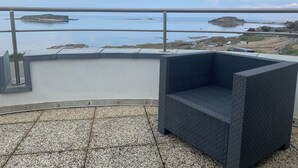 A balcony with a view of rocky coastline and calm sea.