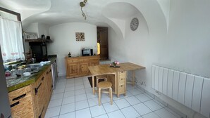 Una cocina con una mesa de madera, un microondas y un reloj en la pared.