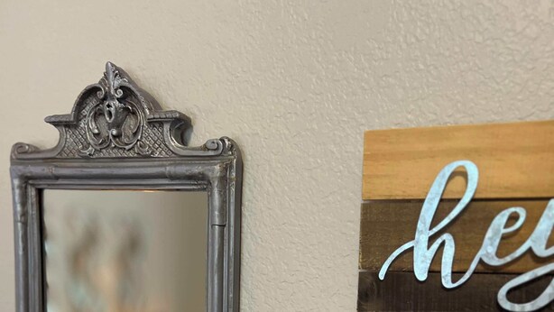 A mirror with an ornate frame, a decorative sign with the word "hey", and a small white ceramic figurine of a llama holding a plant. - Relax in Style! Hot Tub-Pool-Game Room-Sleeps 12 (Allen)