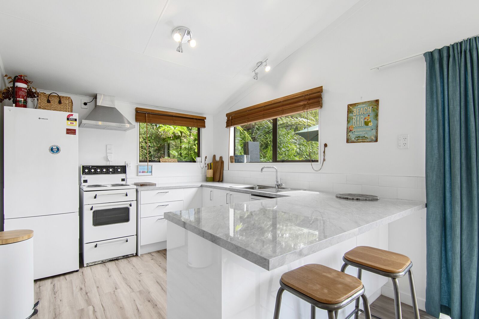 A modern kitchen with a central island, white cabinetry, and a stainless steel sink.