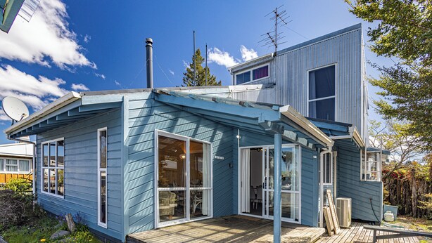 Ein modernes, zweistöckiges Haus mit einer großen Terrasse und Glasschiebefüchern.