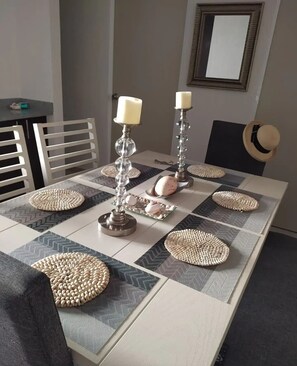 A dining area with a table set for two, featuring woven placemats and ornate candle holders.