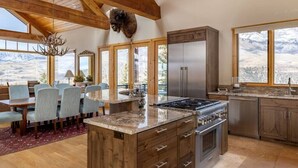 A spacious kitchen with a large island, wooden beams, and a mountain view. - Fairway Vista: Massive Mountain Views w/ hot tub! (Mountain Village)