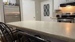 Una cocina con una isla grande, electrodomésticos de acero inoxidable y muebles de color blanco.