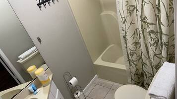A bathroom with a toilet, a sink, a towel rack, and a shower curtain.