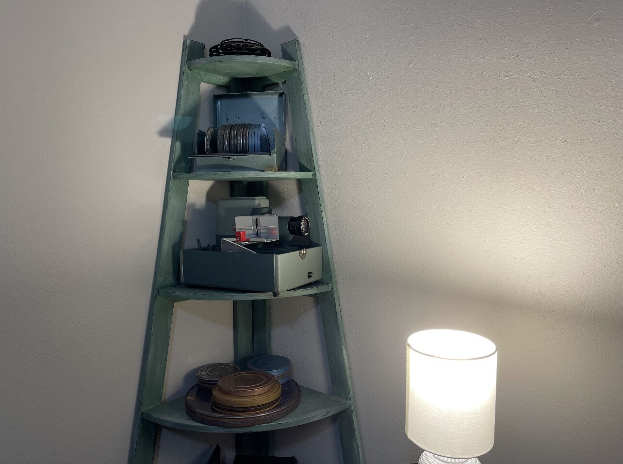 Una scaffalatura a scala con diversi oggetti sopra, tra cui una macchina fotografica e una lampada.