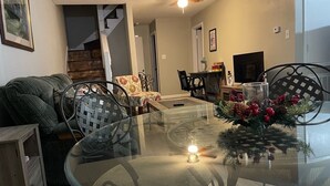 Un comedor con una mesa de vidrio, sillas de metal y una decoración navideña.