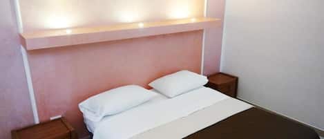 Ein Schlafzimmer mit einem Bett, zwei Nachttischen und einem Regal über dem Bett.